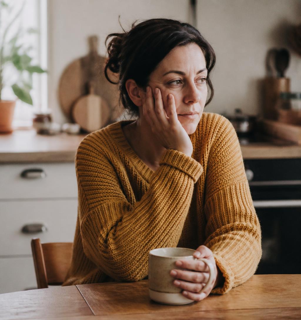 Frau am Küchentisch am Morgen mit einer Tasse Kaffee